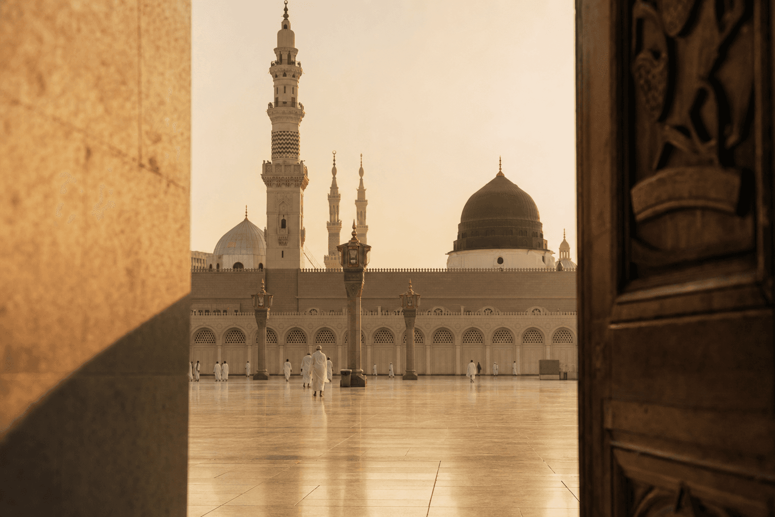 Masjid an-Nabawi at golden hour — warm marble courtyard, green dome, and distant pilgrims in quiet reflection
